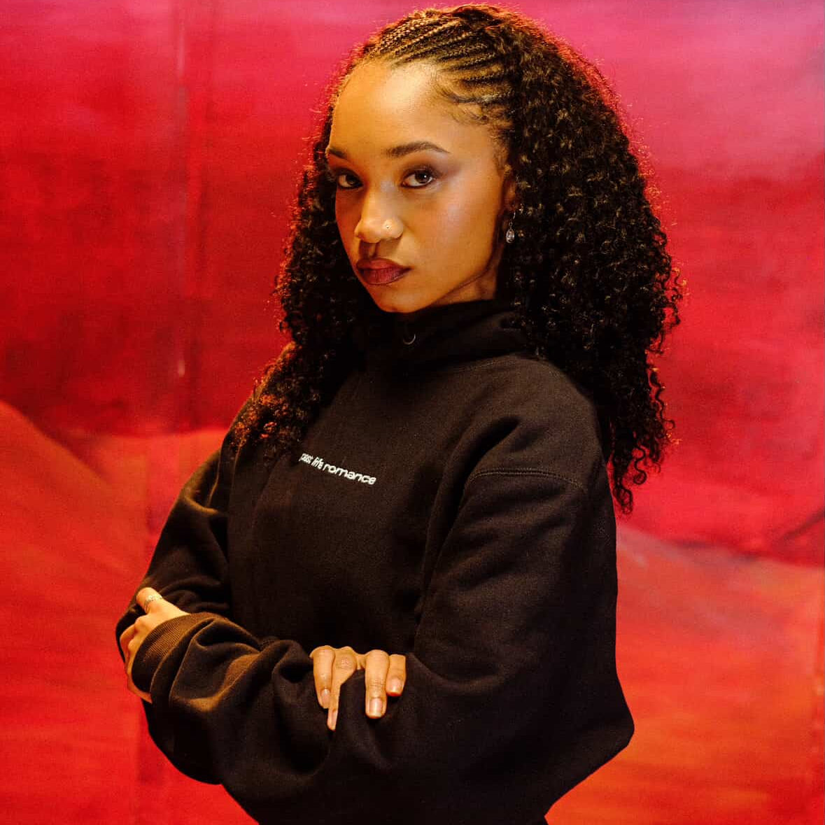 Person wearing a black hoodie with a logo against a red background